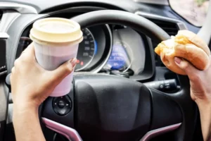 Woman driving while eating and drinking a coffee