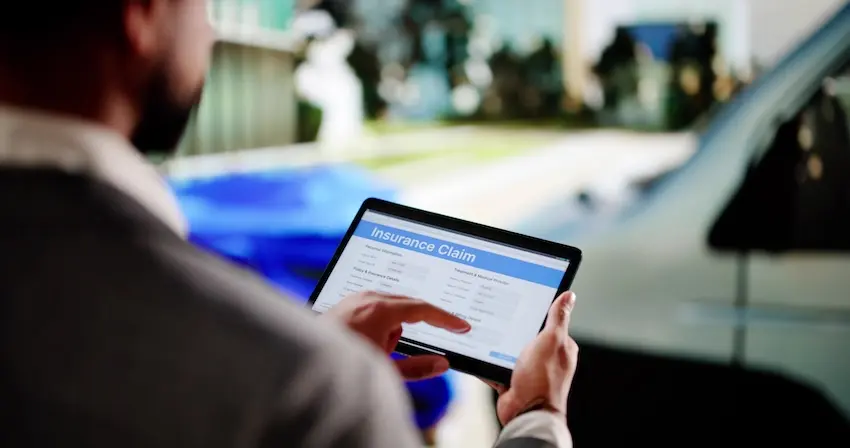 Driver documenting car accident damage at collision scene in Atlanta Georgia for insurance claim