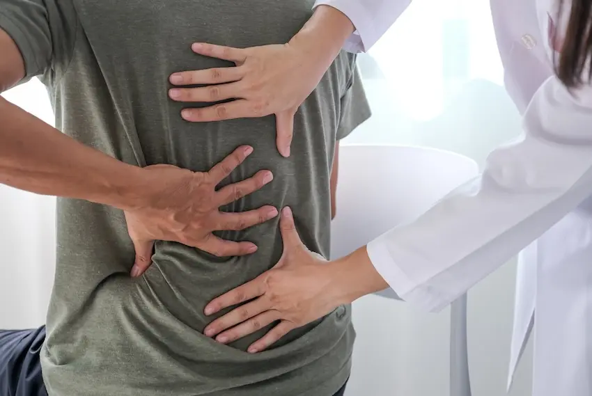 Orthopedic doctor examining patient's spine and reviewing MRI imaging for herniated disc diagnosis after car accident collision