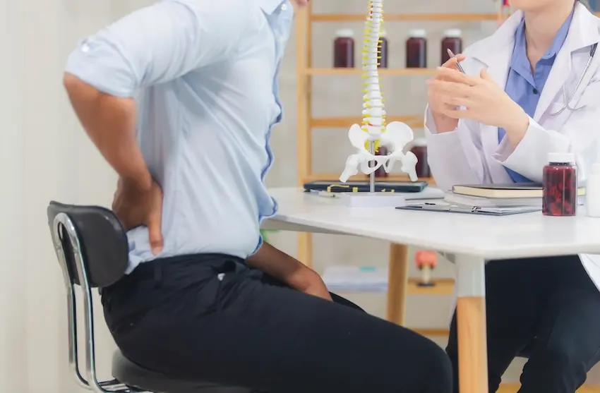 Person holding lower back in pain after car accident showing symptoms of spinal injury and whiplash in Atlanta Georgia