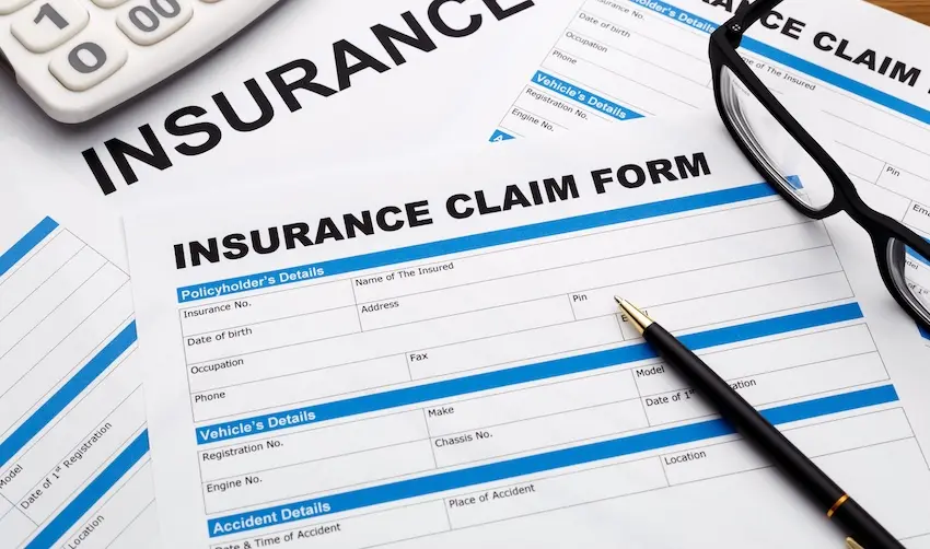 A car insurance claim form with a calculator and a pen and glasses for filing accident damage reimbursement at Atlanta Metro Law.