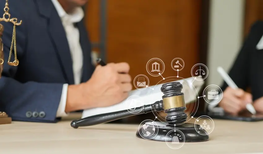 A dark wooden judge's gavel on a sound block sits in the foreground of a law office with a digital overlay of interconnected legal icons including a courthouse- scales of justice- and a gavel while a lawyer from Atlanta Metro Law and client review documents in the background representing the complex legal process involved in pursuing a head-on collision claim.