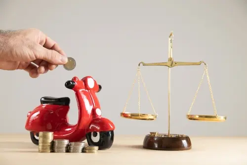 A man holding a coin near a toy motorcycle to represent a motorcycle accident lawyer getting compensation for a victim.